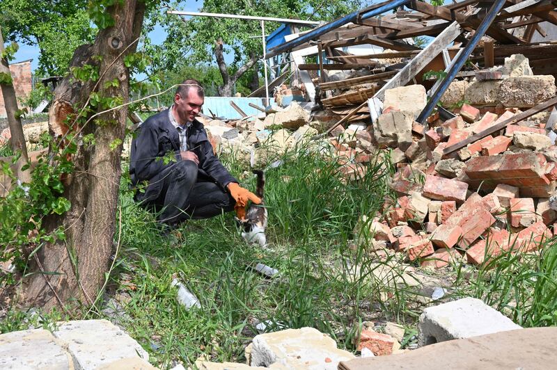 A local resident pets a cat next to a destroyed house in Vilkhivka village, near Kharkiv, Ukraine.  AFP