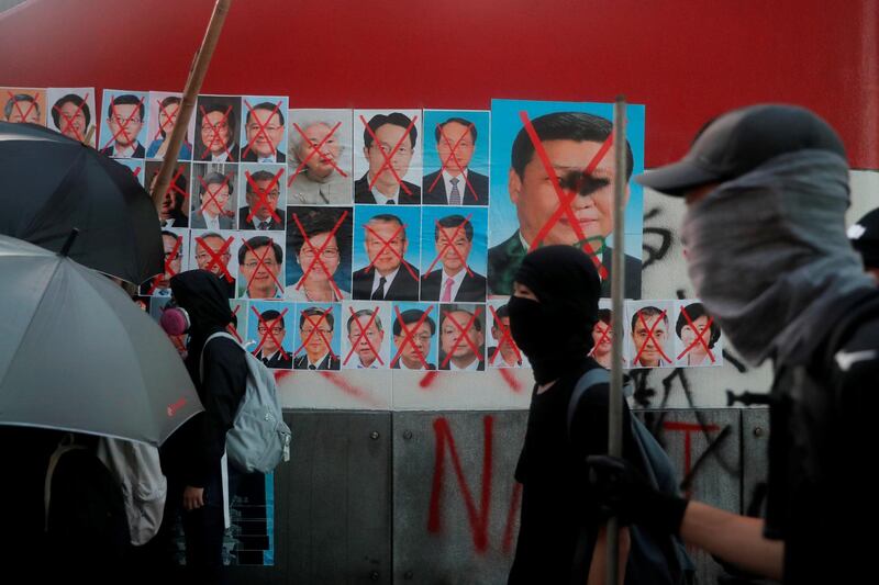 Anti-government protesters walk past defaced pictures of Chinese President Xi Jinping and other members of the government, in Hong Kong. Reuters