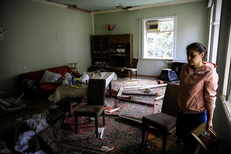 A woman searches for belongings in her damaged house hit by a rocket during the fighting over the breakaway region of Nagorno-Karabakh in the city of Ganja, Azerbaijan. Reuters