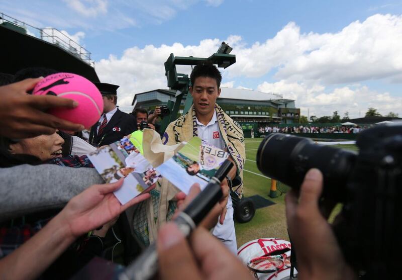 Kei Nishikori of Japan signs autographs after beating Simone Bolelli of Italy in his third-round match on Monday at the 2014 Wimbledon Championships. Andrew Cowie / AFP