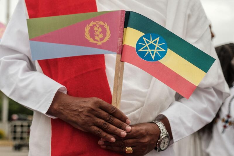 A man holds Narional flags of Eritrea (L) and Ethiopia as he waits for the arrival of Eritrea's President at the airport in Gondar, nothern Ethiopia, on November 9, 2018. The presidents of Somalia and Eritrea met with Ethiopian Prime Minister Abiy Ahmed on Friday to cement regional economic ties as relations warm between the once-rival nations. / AFP / EDUARDO SOTERAS
