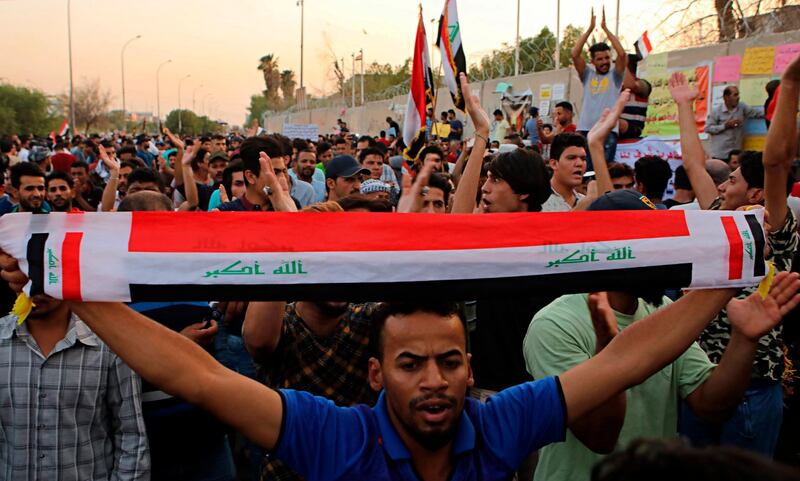 Protesters rise national flags while chanting slogans demanding better public services and jobs during a protest in front of the provincial council building in Basra, 340 miles (550 km) southeast of Baghdad, Iraq, Friday, Aug. 10, 2018. (AP Photo/Nabil al-Jurani)
