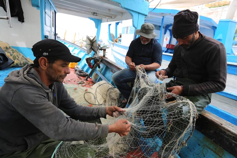 Tunisian fishermen prepare their nets inside a boat in the port of Zarzis. AFP