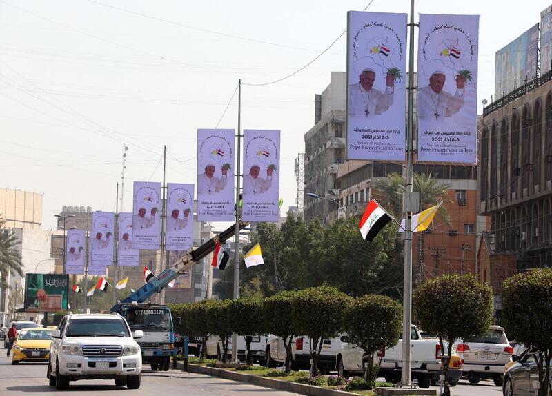 epa09045264 Iraqi workers hang up posters as well as Iraqi and Vatican flags to welcome Pope Francis at a street in central Baghdad, Iraq, 01 March 2021. Pope Francis will be in Iraq for an Apostolic Visit from 05 to 08 March 2021, during which he will pay a courtesy visit to the President and meet with civil authorities and members of the Diplomatic Corps. The Pontiff is scheduled to celebrate Holy Mass at the Chaldean Cathedral of Saint Joseph in Baghdad on Saturday, 06 March 2021.  EPA/AHMED JALIL