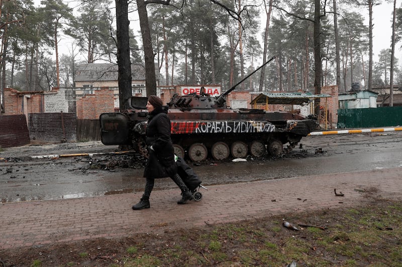 A Ukrainian woman passes destroyed Russian military machinery in Bucha. EPA