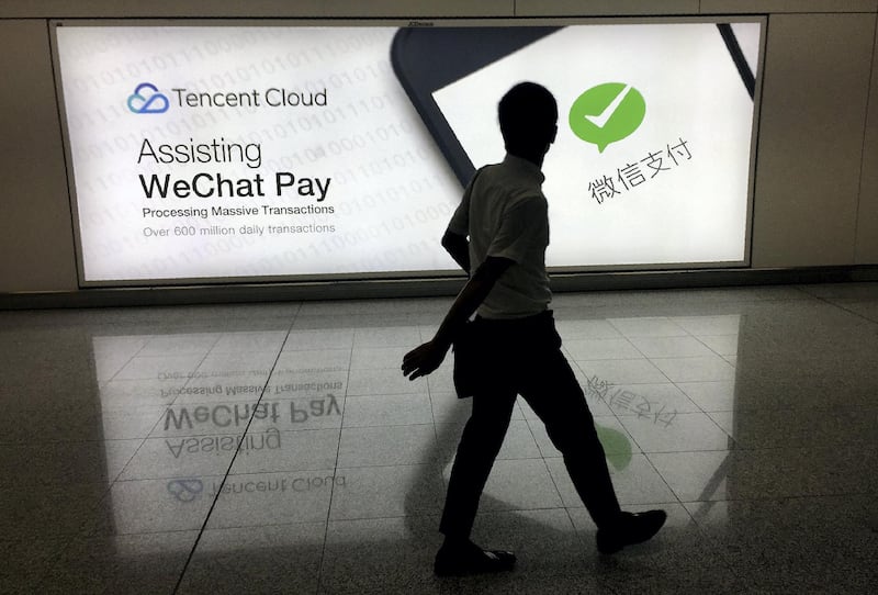 This photo taken on August 21, 2017 shows a man walking at Hong Kong's international airport past an advertisement for the WeChat social media platform owned by China's Tencent company. / AFP PHOTO / Richard A. Brooks