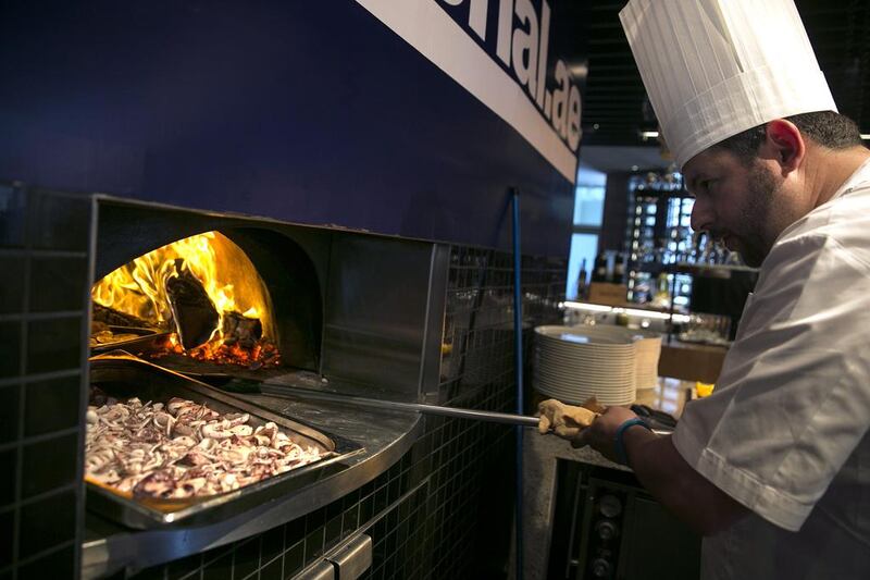 Justin Galea, Executive Chef and Director of Food & Beverage at the Le Royal Meridien hotel in Abu Dhabi, puts food into a wood oven at the #healthyliving cooking experience. Silvia Razgova / The National