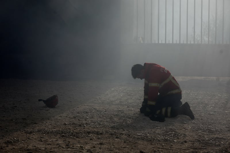 A firefighter kneels on the ground during a fire in Vila Nova de Poiares, Lousa, Portugal. Paulo Cunha / EPA