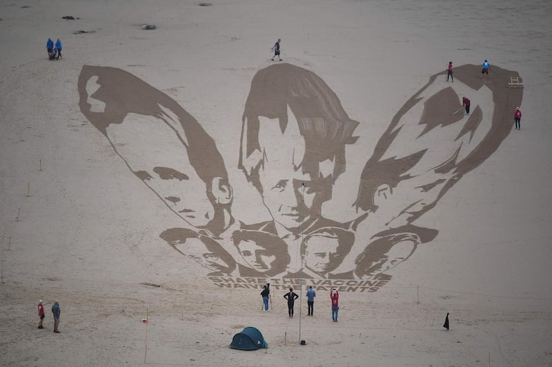 Activists put the finishing touches to a sand drawing of the G7 leaders and calling on them to 'share the vaccine and waive the patents' on Watergate Bay beach near Newquay, Cornwall on June 10, 2021, ahead of the three-day G7 summit being held from 11-13 June.  G7 leaders from Canada, France, Germany, Italy, Japan, the UK and the United States meet this weekend for the first time in nearly two years, for the three-day talks in Carbis Bay, Cornwall. - 
 / AFP / Ben STANSALL
