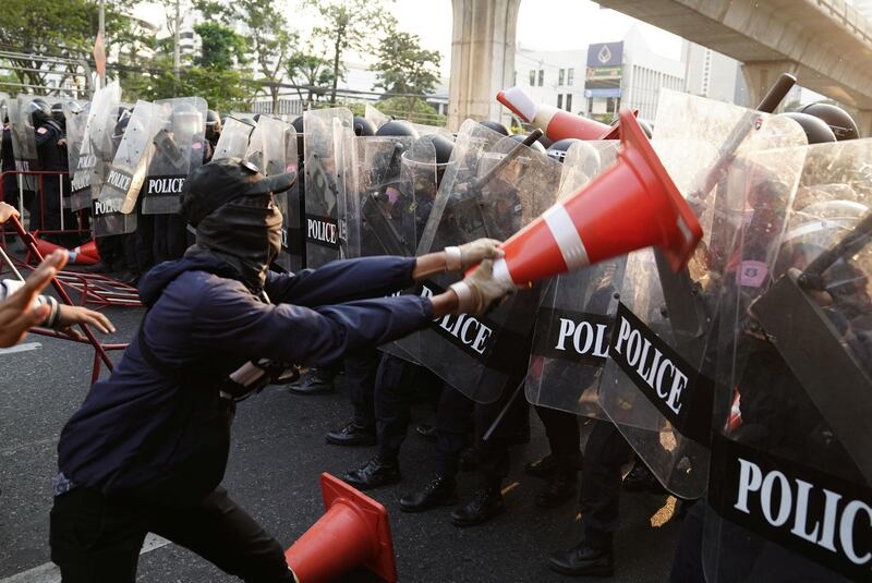 Anti-Thai government protester wields a traffic cone at riot police during a clash at a rally for Myanmar's democracy outside the embassy, in Bangkok, Thailand February 1, 2021. REUTERS/Athit Perawongmetha