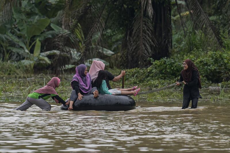 Residents ride inflatable tire tube on a road submerged by floodwater in Kampung Desa Bakti in Malaysia's Pahang State. AFP