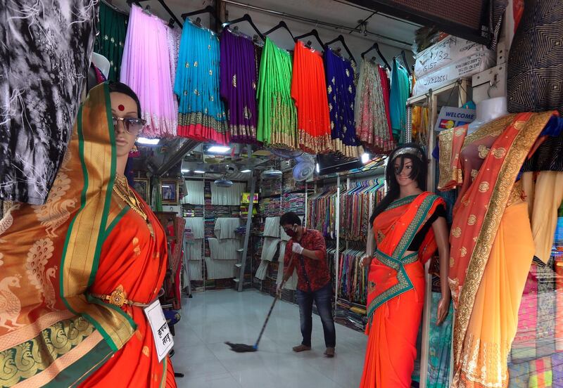 A salesman prepares a cloth shop to receive customers at a shopping centre in Mumbai. AP Photo