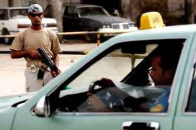 An armed member of the anti-Qaeda Sahwa (Awakening) Council stops cars on October 1, 2008 at a checkpoint in a central Baghdad neighborhood. The US military began transferring control of 100,000 Sunni Arab anti-Qaeda fighters to Iraq's Shiite-led government, a military spokesman told AFP. The Iraqi government and the US military have agreed in principle to the transfer of responsibility of all "Sons of Iraq" from October 1, beginning with 54,000 men in the province of Baghdad. The US military uses the term Sons of Iraq, or "SOIs," to refer to the militia which it recruited from among Sunni tribesmen and former insurgents. AFP PHOTO/AHMAD AL-RUBAYE *** Local Caption ***  385517-01-08.jpg