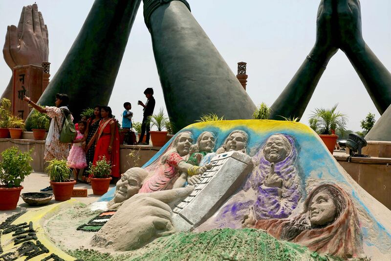 People take selfies beside a sand art sculpture created to spread awareness for citizens to vote on the eve of India's fifth phase of voting during the ongoing general election, at Namo Ghat in Varanasi on May 19, 2024.  (Photo by Niharika KULKARNI  /  AFP)