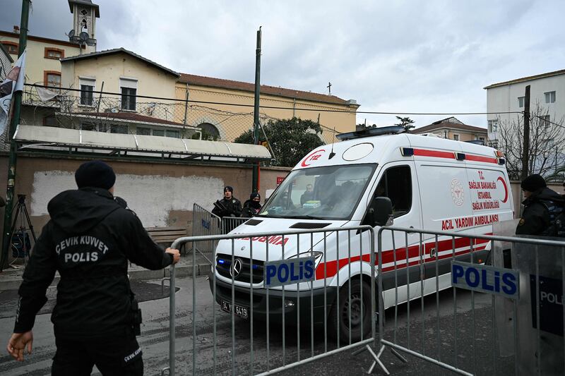 An ambulance leaves Istanbul's Santa Maria church as Turkish riot police block the street after two gunmen carried out a deadly shooting on Sunday. AFP