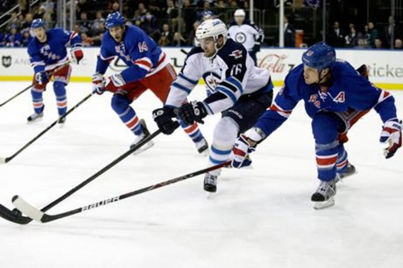 Winnipeg's Andrew Lad battles New York Rangers' Marc Staal for the puck.