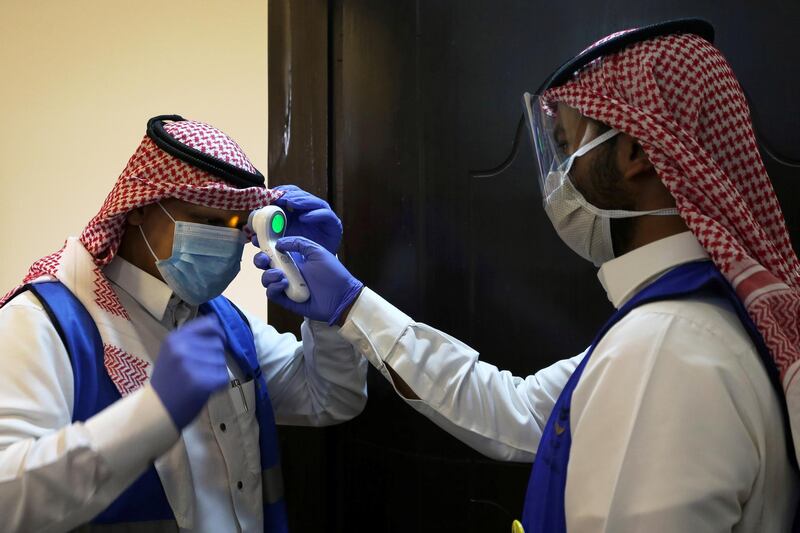 A Saudi volunteer supervisor wearing a protective face mask and gloves checks the temperature of another volunteer before preparing boxes of Iftar meals provided by a charity organisation following the outbreak of the coronavirus disease (COVID-19), during the holy month of Ramadan, in Riyadh, Saudi Arabia May 10, 2020. Picture taken May 10, 2020. REUTERS/Ahmed Yosri