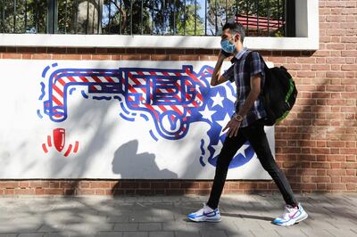 A man, wearing a protective mask amid the COVID-19 pandemic, walks past a mural painted on the outer walls of the former US embassy in the Iranian capital Tehran on September 20, 2020.   Iran called on the rest of the world to unite against the United States, after Washington unilaterally declared UN sanctions against the Islamic republic were back in force. Washington has said it will "impose consequences" on any country not complying with the sanctions, although the US is one of the only nations that believes they are in force.
 / AFP / ATTA KENARE
