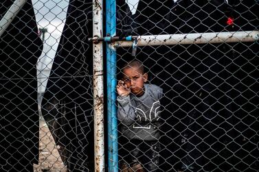 A child waits behind a wire fence door in Al Hol camp, which houses relatives of ISIS members, in northeastern Syria, March 28, 2019. AFP