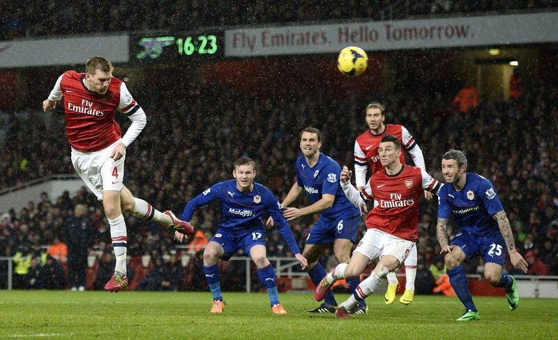 Arsenal's Per Mertesacker, left, heads wide during their English Premier League soccer match against Cardiff City at the Emirates Stadium on Wednesday. REUTERS/Dylan Martinez