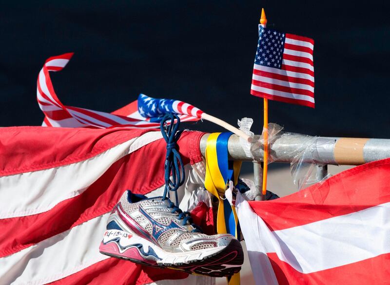 (FILES) In this file photo taken on April 18, 2013 a running shoe and US flag are part of a memorial on the Boston Marathon route in Boston.  A US appeals court overturned the death penalty for Boston Marathon bomber Dzhokhar Tsarnaev on July 31 and ordered a lower court to hold new sentencing hearings. / AFP / Don EMMERT
