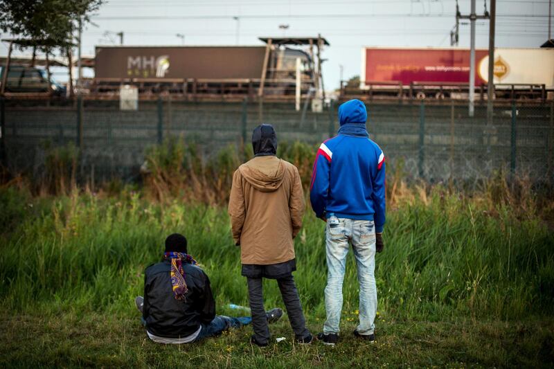 CALAIS, FRANCE - JULY 31:  Men watch as a train arrives at the Eurotunnel terminal in Coquelles on July 31, 2015 in Calais, France.  Hundreds of migrants are continuing to attempt to enter the Channel Tunnel and onto trains heading to the United Kingdom.  Strike action and daily attempts by hundreds of migrants to enter the Channel Tunnel and onto trains heading to the United Kingdom is causing delays to passenger and freight services across the channel.  British Prime Minster David Cameron has announced that extra sniffer dogs and fencing are to be sent to Calais and land owned by the Ministry of Defence is to be used as a lorry park to ease congestion near the port of Dover in Kent. (Photo by Rob Stothard/Getty Images)
