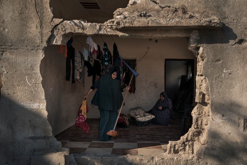 Jawaher Nassir cleans a room inside her home, heavily damaged by air strikes. Five decades ago, her husband's father moved his family to a plot of farmland in what was then a village. Today, three- and four-storey homes along Al Baali Street are filled with Nassirs. AP