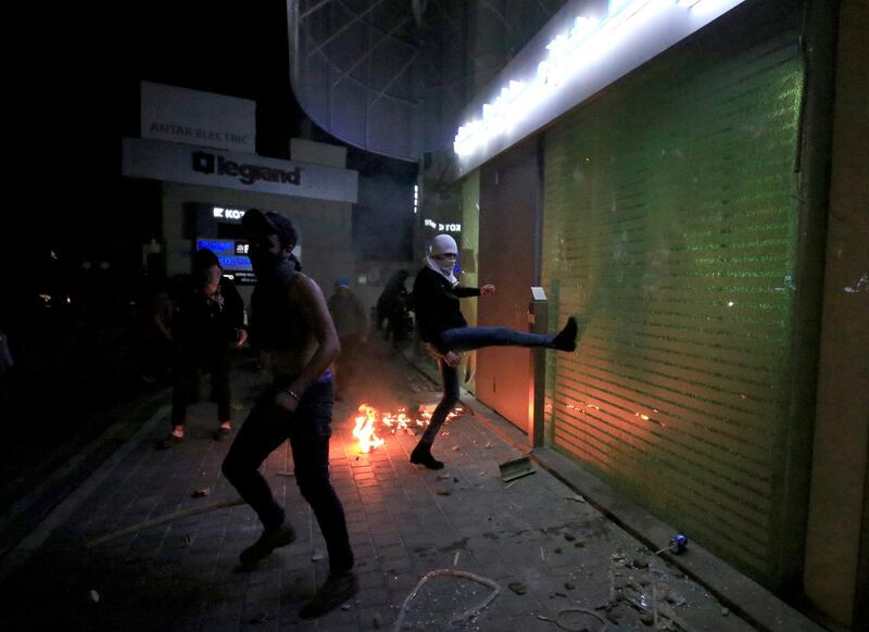 A demonstrator smashes a window of a bank during a protest against growing economic hardship in Sidon, Lebanon. Reuters