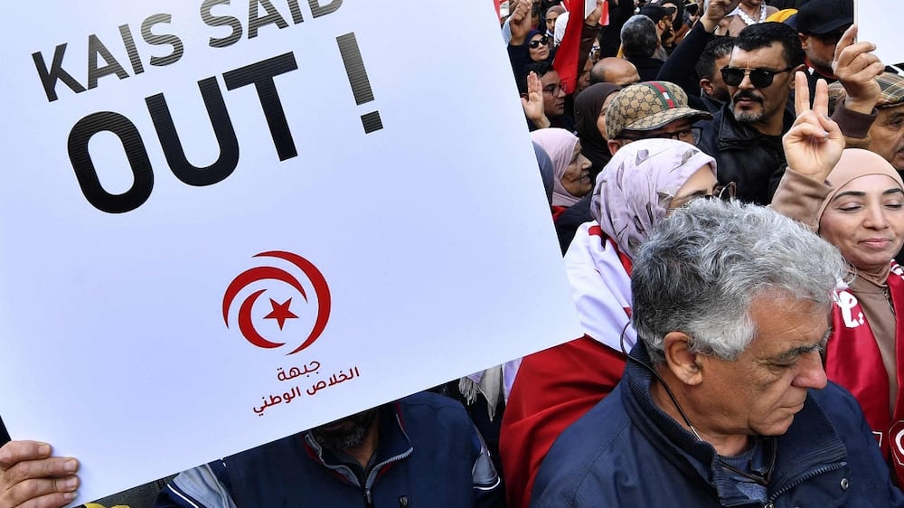 Tunisian demonstrators carry placards during a protest in central Tunis against their president on January 14, 2023.  - In July 2021, President Kais Saied sacked the government, froze parliament and seized far-reaching executive powers, later grabbing control of the judiciary -- moves opponents said aimed to install a new dictatorship in the birthplace of the Arab Spring uprisings.  (Photo by FETHI BELAID  /  AFP)