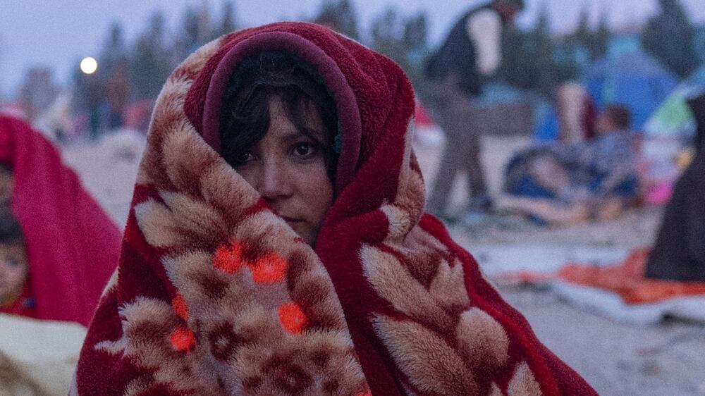 An Afghan woman is wrapped in a blanket as she and her family camp outside the Directorate of Disaster that they camp, in Herat, Afghanistan, Monday, Nov.  29, 2021.  About 2000 internally displaced people left Allahyar village of Ghor province because of the drought that worsened their economic situation and asking help from the regional government in Herat.  (AP Photo / Petros Giannakouris)