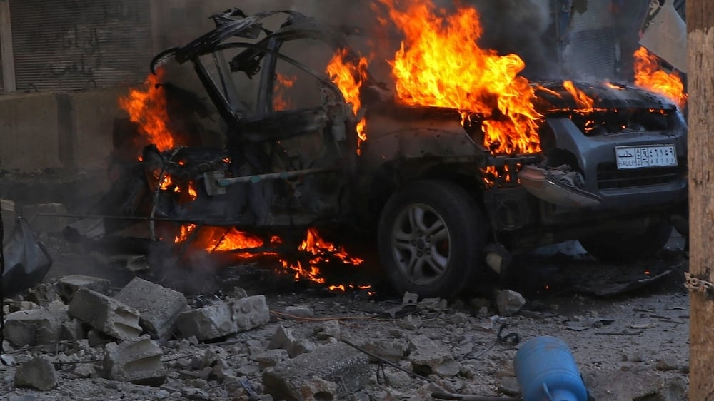 This photo provided by the Syrian Civil Defense White Helmets, which has been authenticated based on its contents and other AP reporting, shows Syrians around a burning car hit by a shell, in the town of Afrin, north of Aleppo, Thursday, Jan.  20, 2022.  The rocket attack on Afrin, controlled by Turkey-backed opposition fighters, killed several civilians and wounded over a dozen people on Thursday, Syrian rescuers and a war monitor said.  Both blamed U. S-backed Syrian Kurdish forces for the attack.  (Syrian Civil Defense White Helmets via AP)