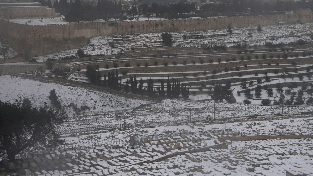 Snow covers the Mount of Olives Jewish cemetery with a view of the Dome of the Rock in the Al-Aqsa Mosque compound in the background, in Jerusalem, Thursday, Jan.  27, 2022.  A rare snowfall hit parts of Israel and the West Bank, closing schools and businesses.  (AP Photo / Mahmoud Illean)