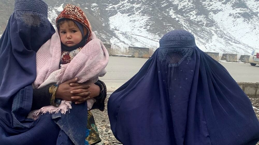 Gulnaz, left, keep her 18-month-old son warm themselves as they wait for alms in the Kabul - Pul-e-Alam highway eastern Afghanistan, Tuesday, Jan.  18, 2022.  The Taliban's sweep to power in Afghanistan in August drove billions of dollars in international assistance out of the country and sent an already dirt-poor poor nation, ravaged by war, drought and floods, spiralling toward a humanitarian catastrophe.  (AP Photo / Kathy Gannon)