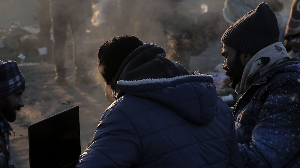 Refugees try to stay warm after fleeing the Russian invasion of Ukraine, at the Medyka border crossing in Poland, Tuesday, March 1, 2022.   All day long, as trains and buses bring people fleeing Ukraine to the safety of Polish border towns, they carry not just Ukrainian fleeing a homeland under attack but large numbers of other citizens who had made Ukraine their home and whose fates too are now uncertain.  (AP Photo / Visar Kryeziu)