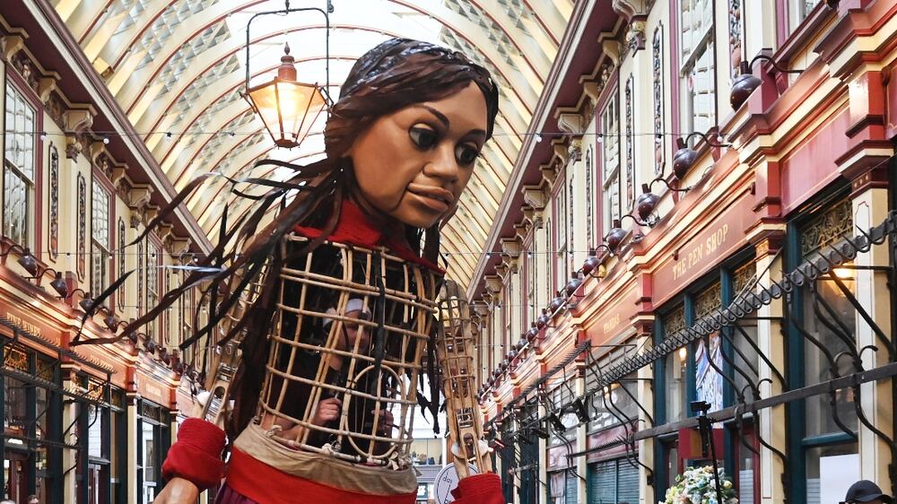 Puppeteers manipulate a marionette of an over-sized refugee child during a PR stunt in Leadenhall Market in London, Britain, 29 March 2023.  The 3. 5 meter puppet, known as 'Little Amal' represents a 10-year-old Syrian refugee.  It was paraded through London to raise money for displaced children on behalf of the Choose Love organization.   EPA / NEIL HALL