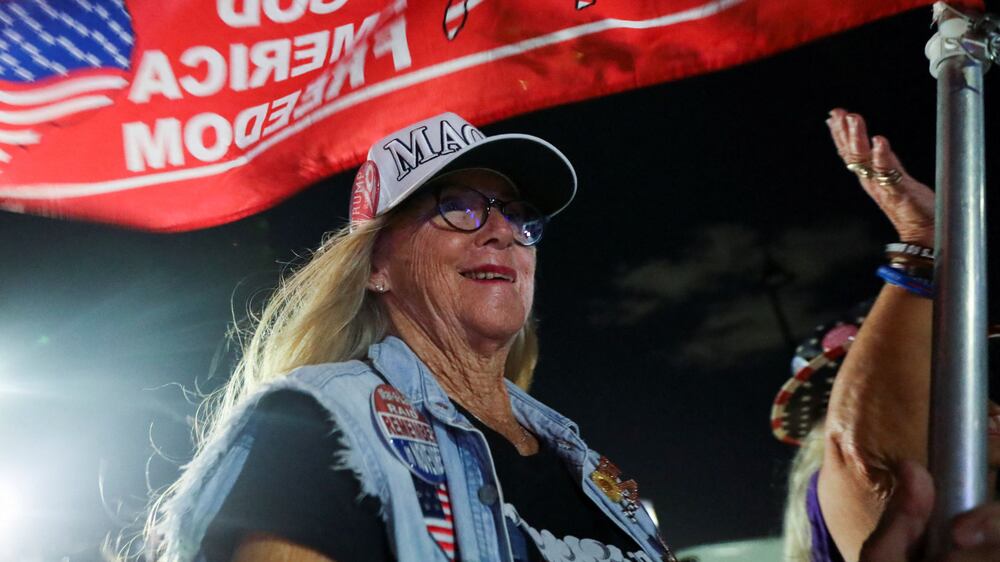 A supporter of former U. S.  President Donald Trump attends a gathering outside his Mar-a-Lago resort after hearing news of Trump's indictment by a Manhattan grand jury following a probe into hush money paid to porn star Stormy Daniels, in Palm Beach, Florida, U. S. , March 30, 2023.  REUTERS / Maria Alejandra Cardona