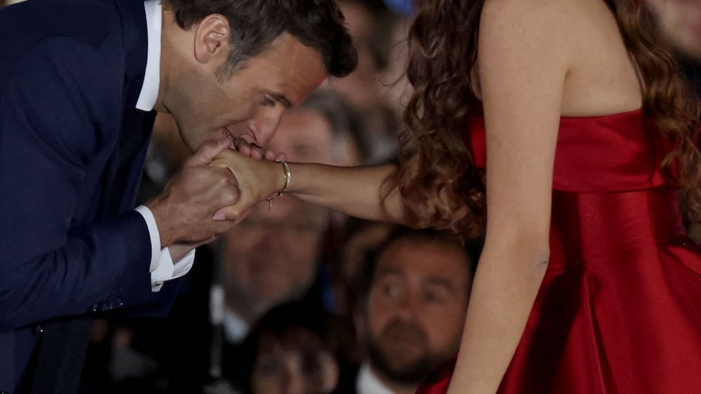 French President and La Republique en Marche (LREM) party candidate for re-election Emmanuel Macron (L) kisses the hand of Egyptian opera singer Farrah El Dibany after his victory in France's presidential election, at the Champ de Mars in Paris, on April 24 , 2022.  (Photo by Thomas COEX  /  AFP)