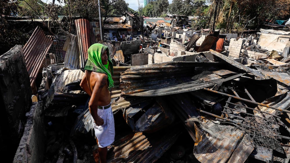 A citizen looks on at burnt belongings and debris scattered in a residential compound following a fire in Quezon City, Metro Manila, Philippines 02 May 2022.  Eight people, including three minors, died in the blaze that hit some 80 houses according to the Bureau of Fire Protection.   EPA / ROLEX DELA PENA