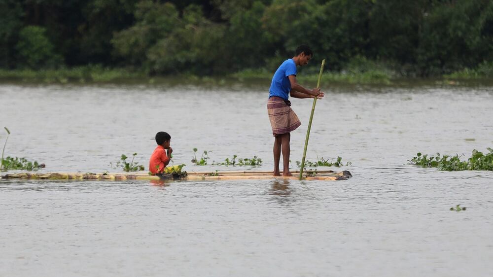 A man and a child travel on a wooden plank through flood waters in Bagha area in Sylhet, Bangladesh, Monday, May 23, 2022.  Pre-monsoon deluges have flooded parts of India and Bangladesh, killing at least 24 people in recent weeks and sending 90,000 people into shelters, authorities said Monday.  (AP Photo)