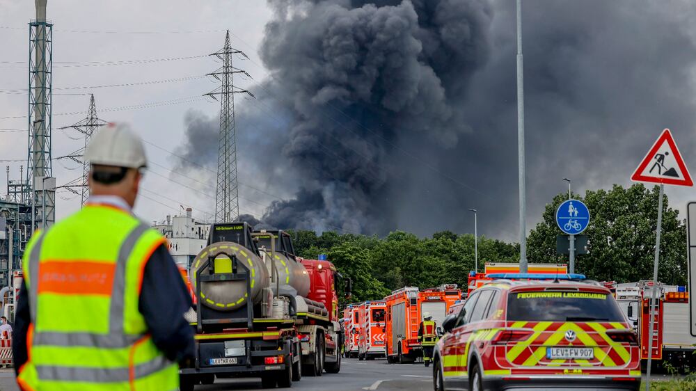 Emergency vehicles of the fire brigade, rescue services and police stand not far from an access road to the Chempark over which a dark cloud of smoke is rising in Leverkusen, Germany, Tuesday, July 27, 2021. .  After an explosion, fire brigade, rescue services and police are currently in large-scale operation, the police explained.  (Oliver Berg / dpa via AP)