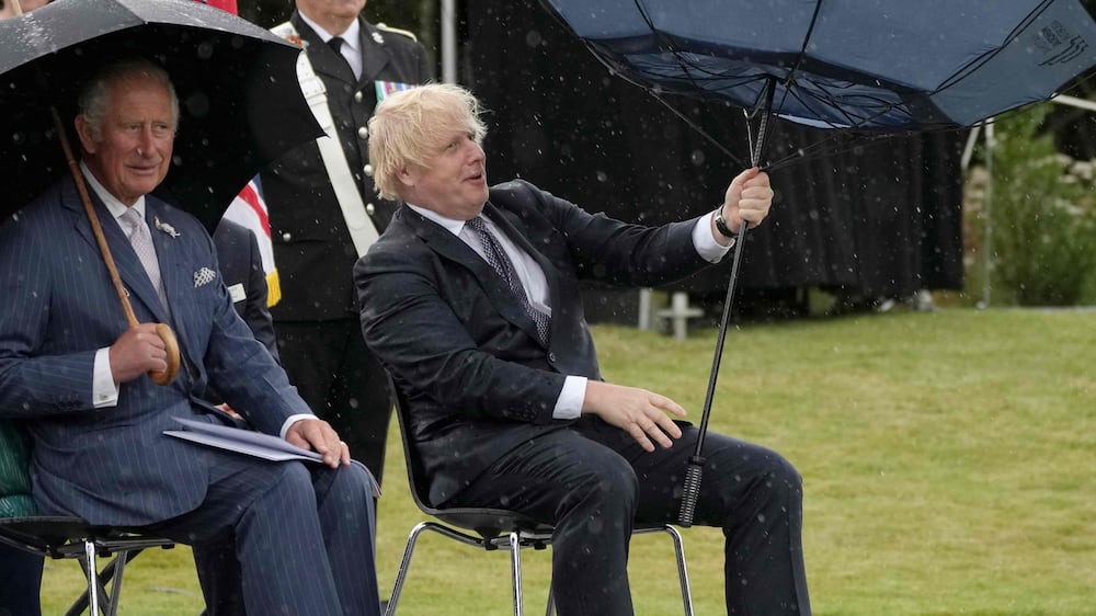 Britain's Prime Minister Boris Johnson (R) tries to open his umbrella next to Britain's Prince Charles, Prince of Wales (L), at the dedication ceremony of the new national UK Police Memorial at the National Memorial Arboretum in Alrewas, central England, on July 28, 2021.  - The 12-metre high brass memorial designed by architect Walter Jack commemorates the courage and sacrifice of members of the UK Police service.  Since the establishment of the Bow Street Runners in 1749, almost 5,000 police officers and staff have died on duty, 1,500 from acts of violence.  (Photo by Christopher Furlong  /  POOL  /  AFP)