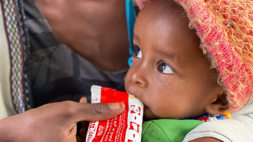 Amanuel Berhanu, held by his mother, eats emergency food after being screened for malnutrition in Debub Health Centre in Wajirat woreda in Southern Tigray in Ethiopia, Monday July 19, 2021.  More than 100,000 children in Ethiopia���s embattled Tigray region could face the most extreme and life-threatening form of malnutrition in the next year, the United Nations children���s agency warned on Friday July 30, 2021, as humanitarian aid remains blocked from the region of some 6 million people.  (UNICEF via AP)