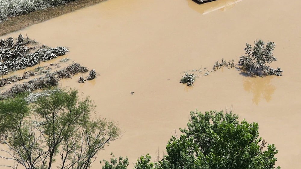 In this aerial photo, some homes in Breathitt County, Ky. , are still surrounded by water on Saturday, July 30, 2022, after historic rains flooded many areas of Eastern Kentucky killing multiple people.  A thin film of mud from the retreating waters covers many cars and homes.  (Michael Clevenger / Courier Journal via AP)