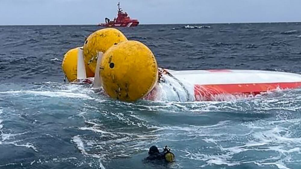 This handout photograph released on August 4, 2022 by the Spanish Salvamento Maritimo sea search and rescue agency shows a rescue diver approaching the capsized French-flagged Jeanne Solo Sailor sailboat, 22 kilometres off the coasts of the Sisargas islands, in the Galicia region, north-western Spain.  - The French sailor has been rescued after being trapped for hours inside his capsized sailboat.  (Photo by Handout  /  SALVAMENTO MARITIMO  /  AFP)  /  RESTRICTED TO EDITORIAL USE - MANDATORY CREDIT "AFP PHOTO  /  SALVAMENTO MARITIMO" - NO MARKETING - NO ADVERTISING CAMPAIGNS - DISTRIBUTED AS A SERVICE TO CLIENTS