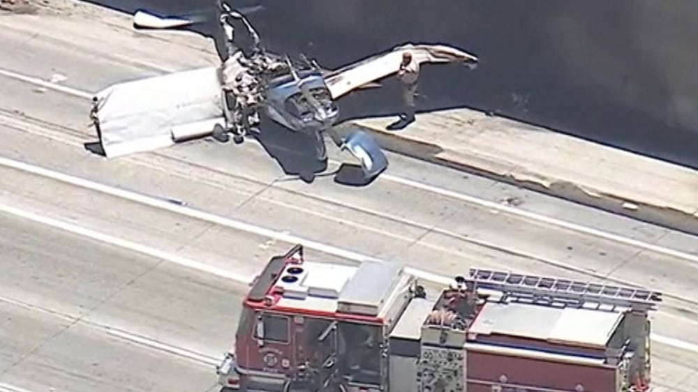 Plane crash lands on California motorway and catches fire