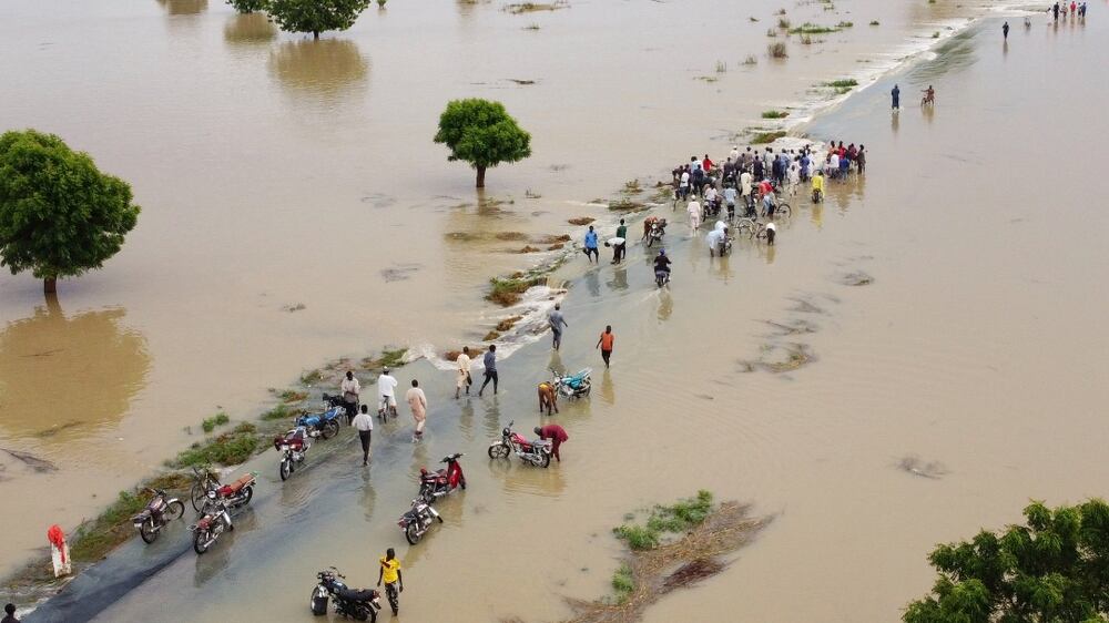 Peole walk through floodwaters after heavy rainfall in Hadeja, Nigeria, Monday, Sept 19, 2022.  Nigeria is battling its worst floods in a decade with more than 300 people killed in 2021 including at least 20 this week, authorities told the Associated Press on Monday.  (AP Photo)