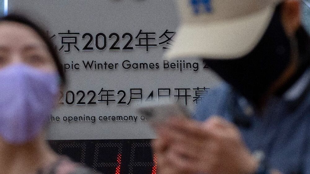 People wearing face masks to protect against COVID-19 walk past a display showing a countdown clock to the Beijing 2022 Winter Olympics in Beijing, Wednesday, Aug.  18, 2021.  China's "zero tolerance" strategy of trying to isolate every case and stop transmission of the coronavirus has kept kept the country where the virus first was detected in late 2019 largely free of the disease.  (AP Photo / Mark Schiefelbein)