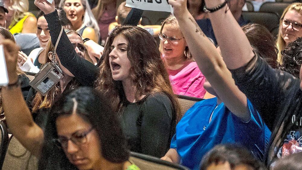 FILE - In this Aug.  25, 2021 file photo, people hold signs and chant during a meeting of the North Allegheny School District school board regarding the district's mask policy, at at North Allegheny Senior High School in McCandless, Pa.  The nation's school boards are asking President Joe Biden for federal assistance to investigate and stop a growing number of threats made against their members, on Thursday, Sept.  30.    (Alexandra Wimley / Pittsburgh Post-Gazette via AP, File)