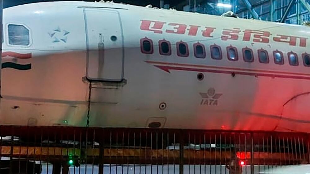 A scrapped Air India aircraft is seen stuck under a pedestrian overbridge in New Delhi, India, Sunday, Oct.  3, 2021.  The plane was reportedly being transported by its new owner who purchased it from the airline.  (Kshitiz Kakkar via AP)
