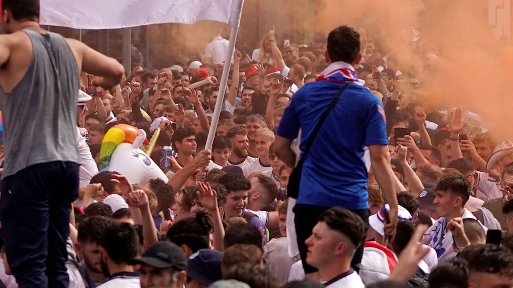 (FILES) In this file photo taken on July 11, 2021 England fans cheer on their team outside Wembley Stadium ahead of the UEFA EURO 2020 final football match between England and Italy in northwest London.  - England must play their next home match in a UEFA competition behind closed doors following disorder at the Euro 2020 final at Wembley, European football's governing body ruled on October 18, 2021.  The showpiece game between England and Italy on July 11 was marred by chaotic scenes as ticketless supporters forced their way through security cordons to gain entry to the stadium.  (Photo by Niklas HALLE'N  /  AFP)